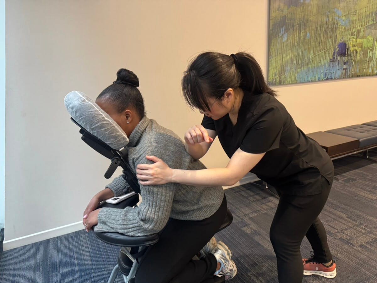 Knead NYC therapist providing chair massage during an office wellness session