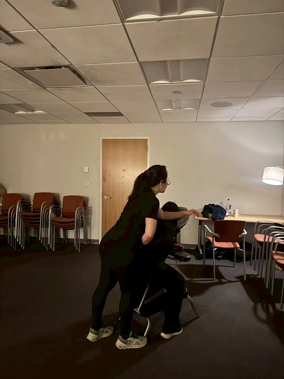 Therapist providing chair massage during a corporate event in a conference room