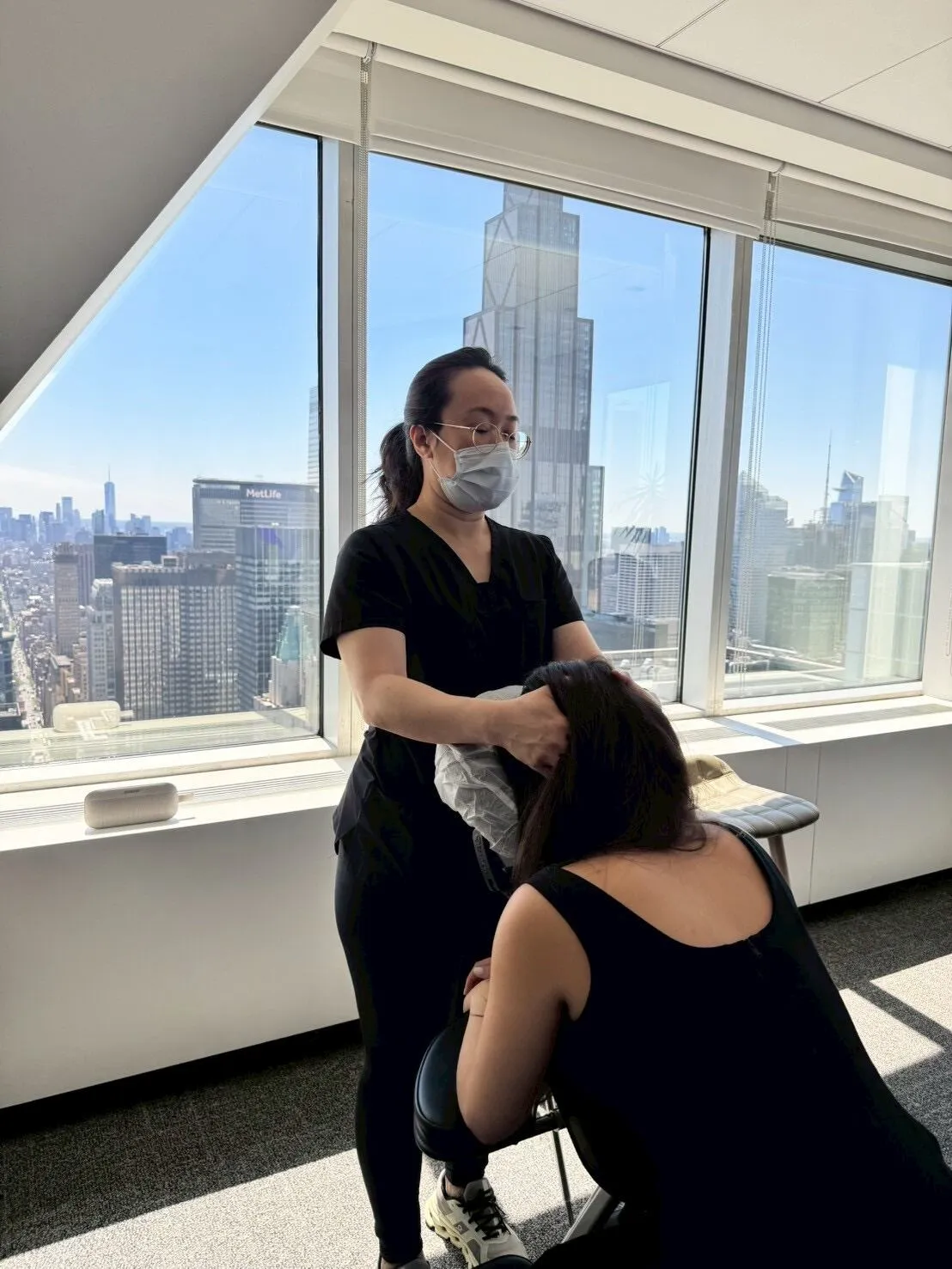 Knead NYC therapist giving chair massage in a Manhattan office with skyline views