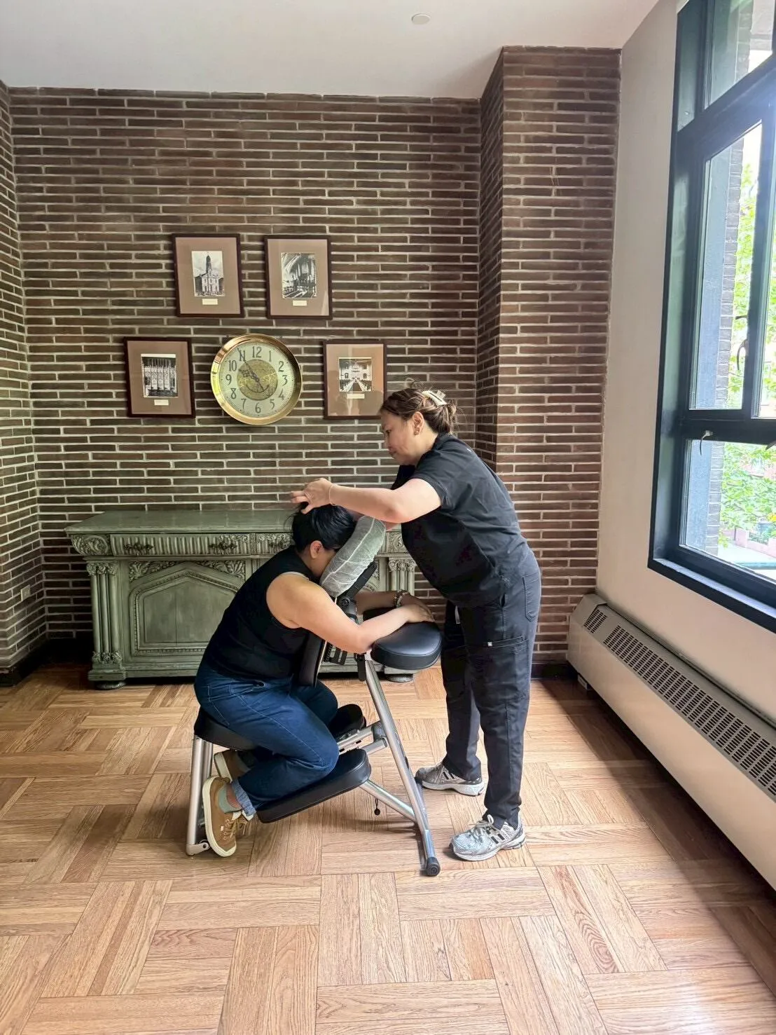 Two guests receiving chair massages at an event in a sunlit room