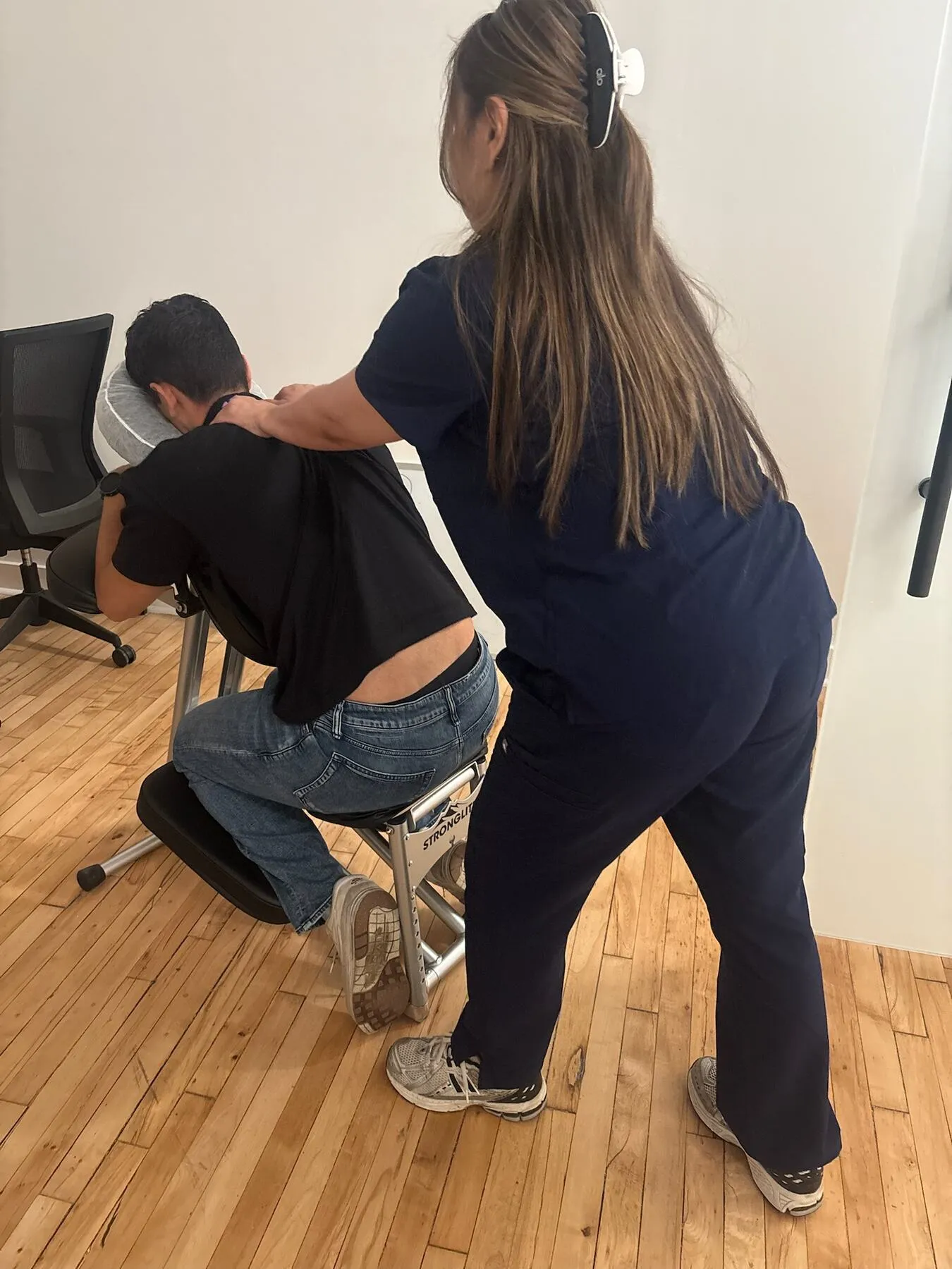 Knead NYC therapist giving an on-site chair massage in a bright corporate office