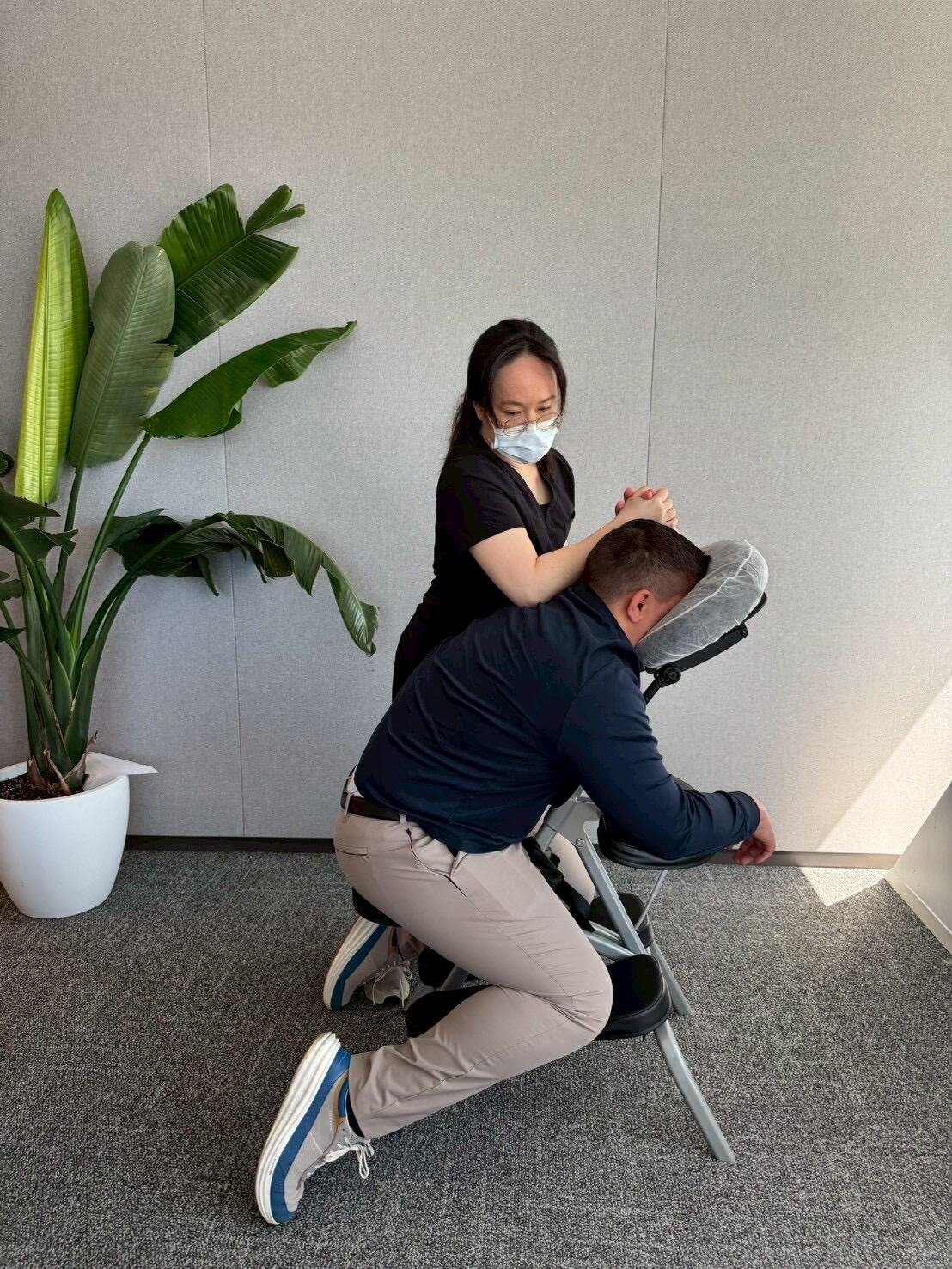 Employee receiving chair massage beside a large plant in a modern office