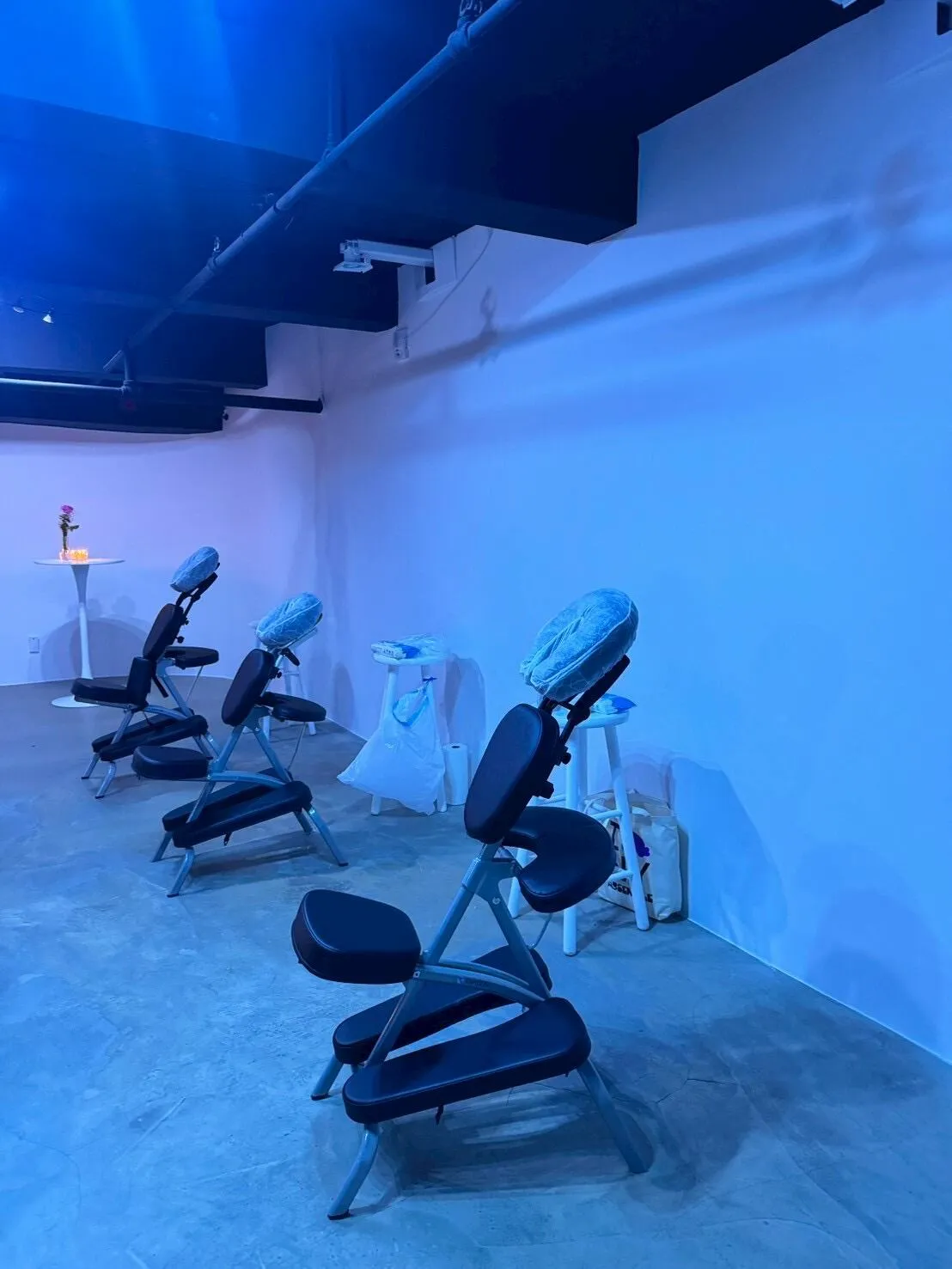 Multiple massage chairs arranged for an event in a blue-lit New York venue