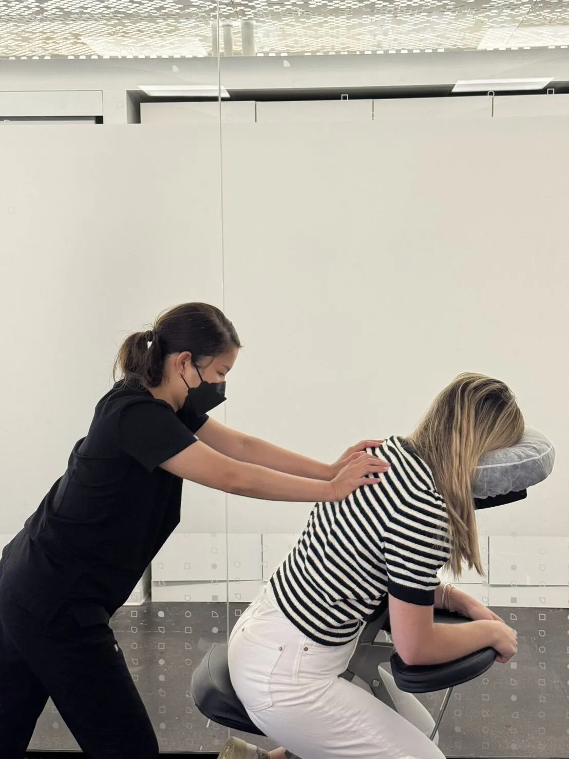 Therapist massaging an employee's shoulders during an office wellness event