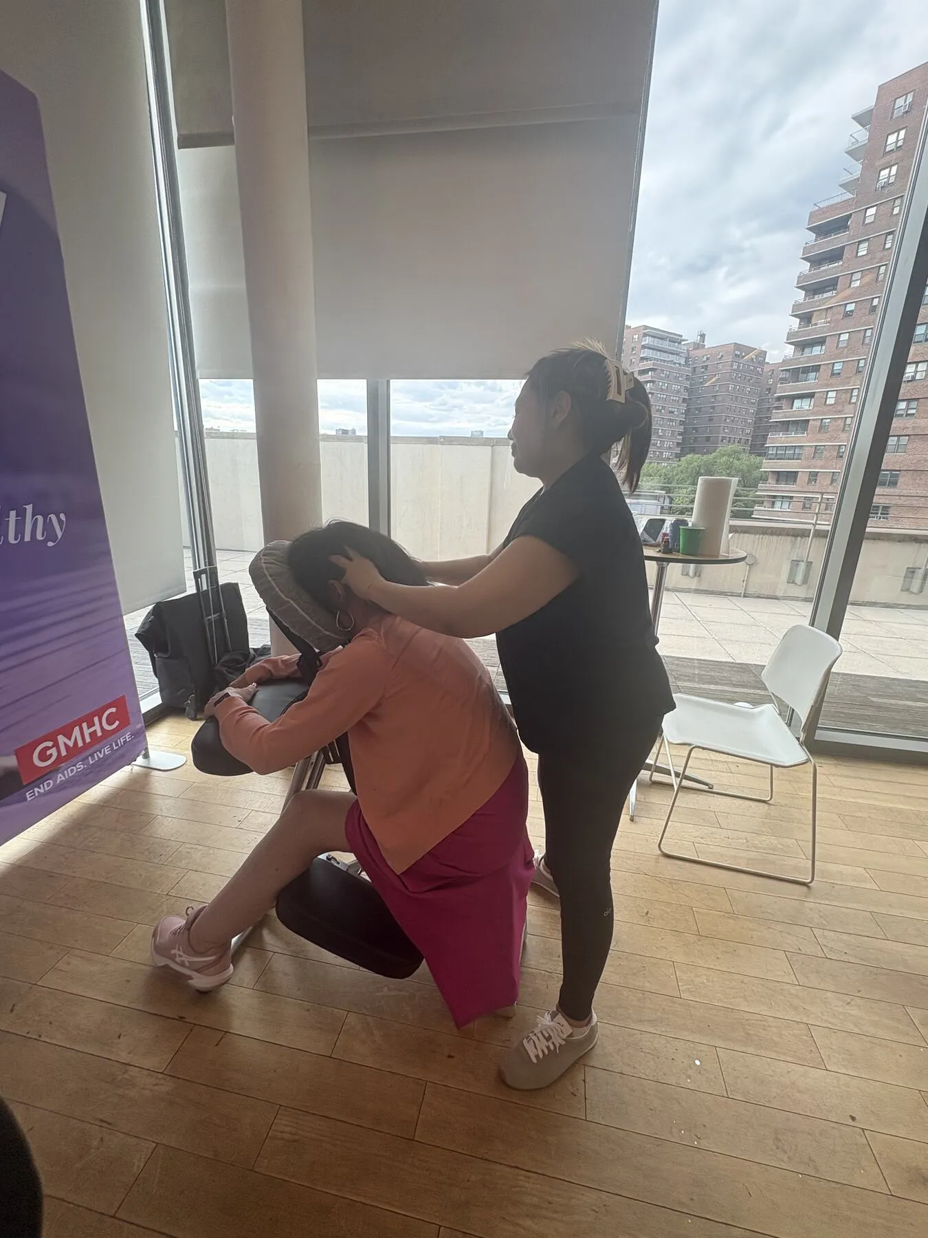 Knead NYC therapist providing chair massage at a GMHC workplace wellness event