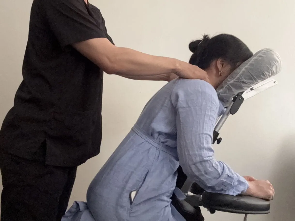 Close-up of a therapist relieving neck and shoulder tension with chair massage