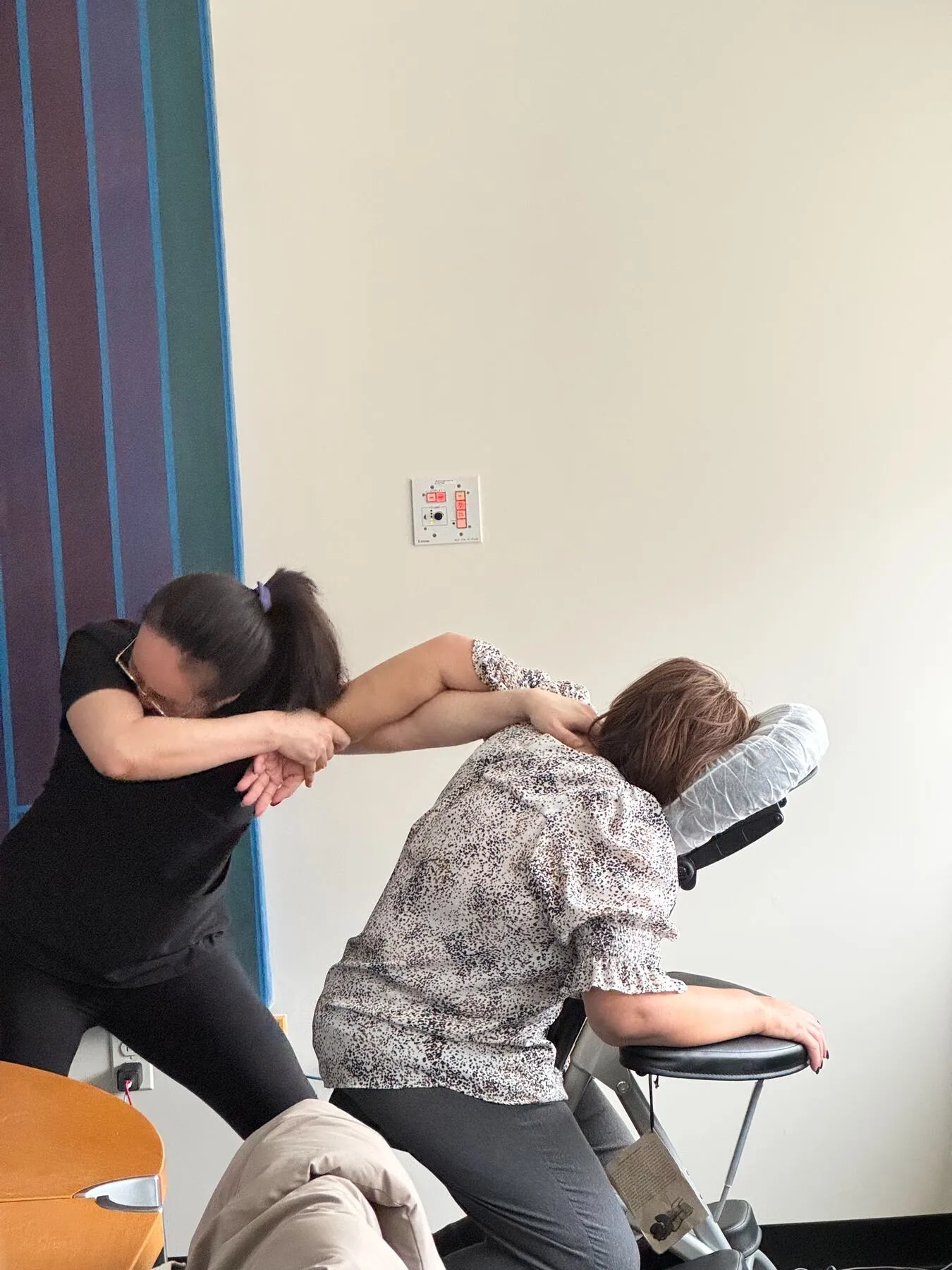Therapist giving chair massage beside a conference table at a corporate office