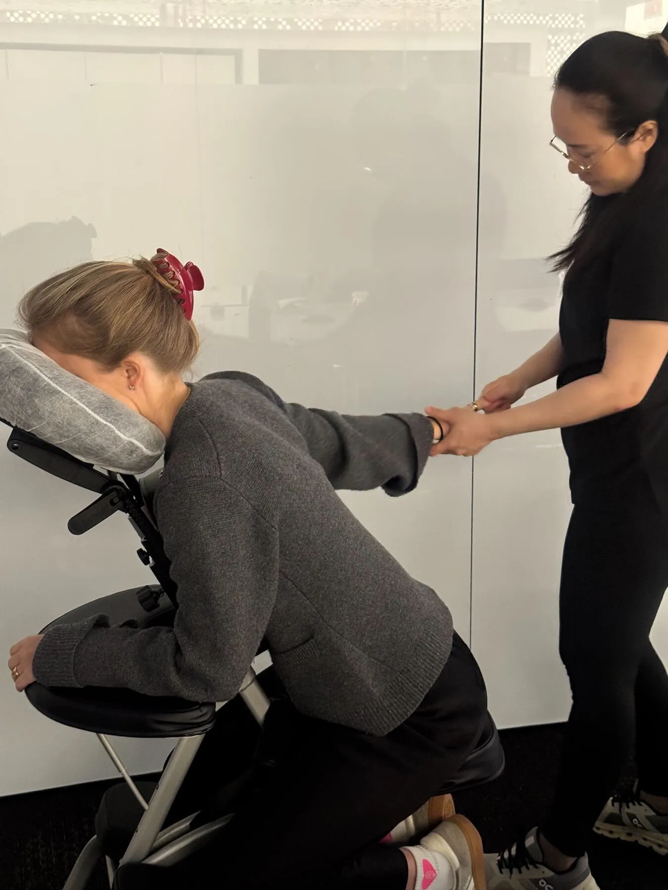Massage therapist gently stretching a client's arm during a seated session