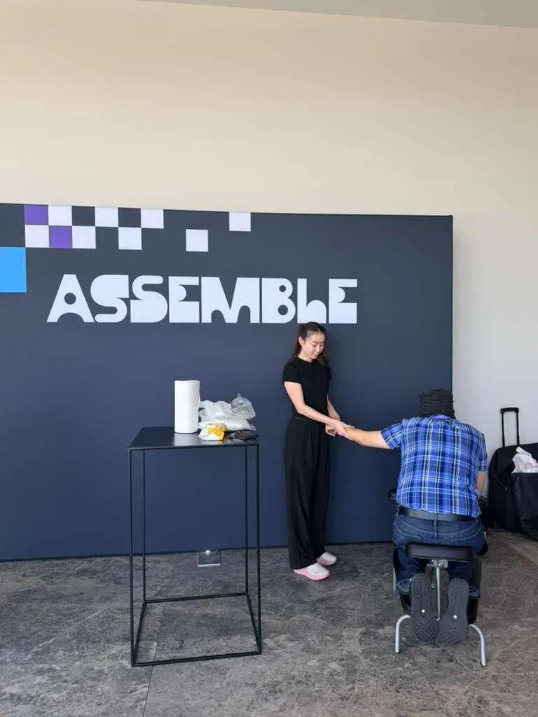 On-site chair massage activation in front of the ASSEMBLE office wall