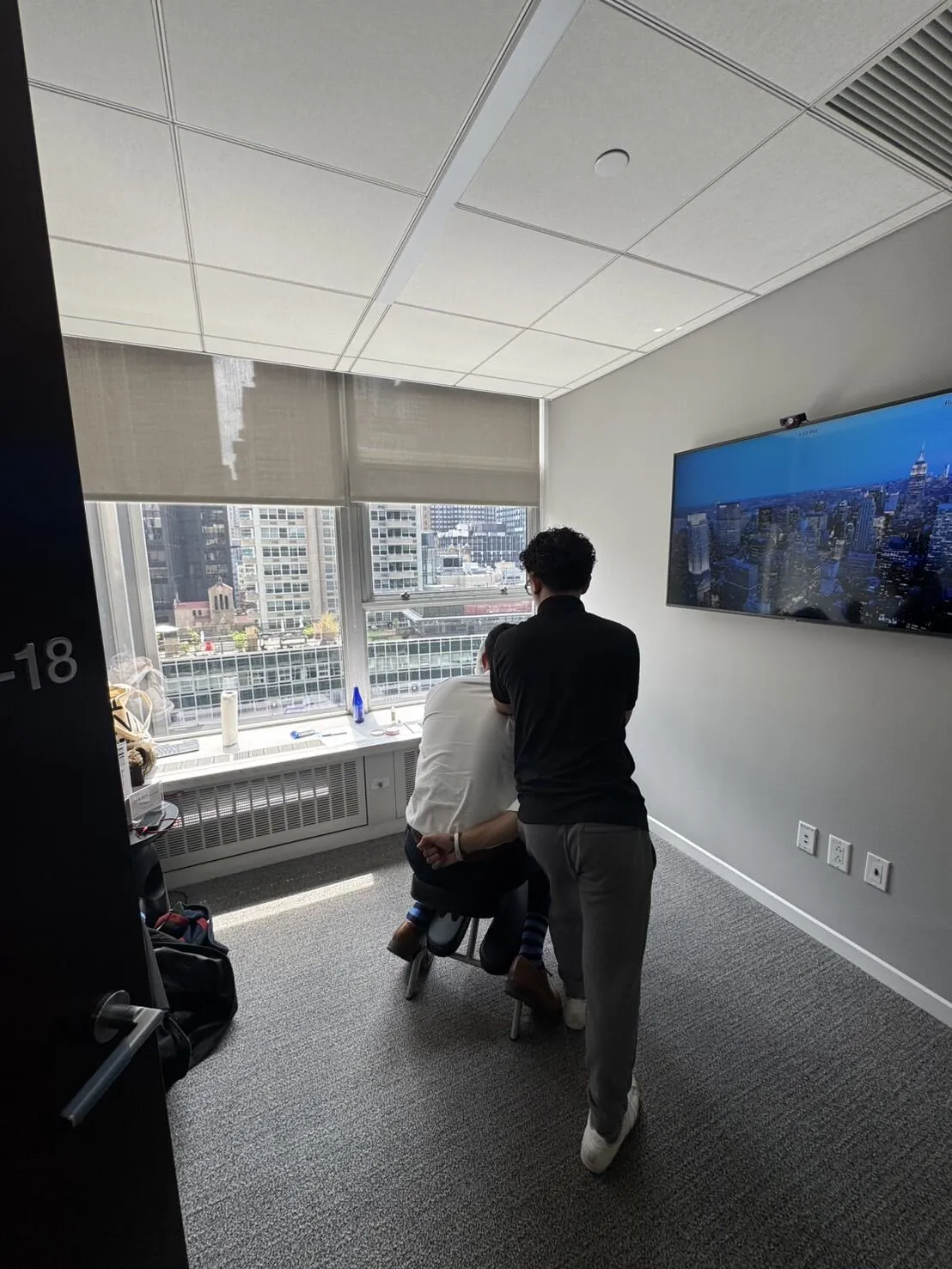 Massage therapist providing workplace chair massage beside a Manhattan office window