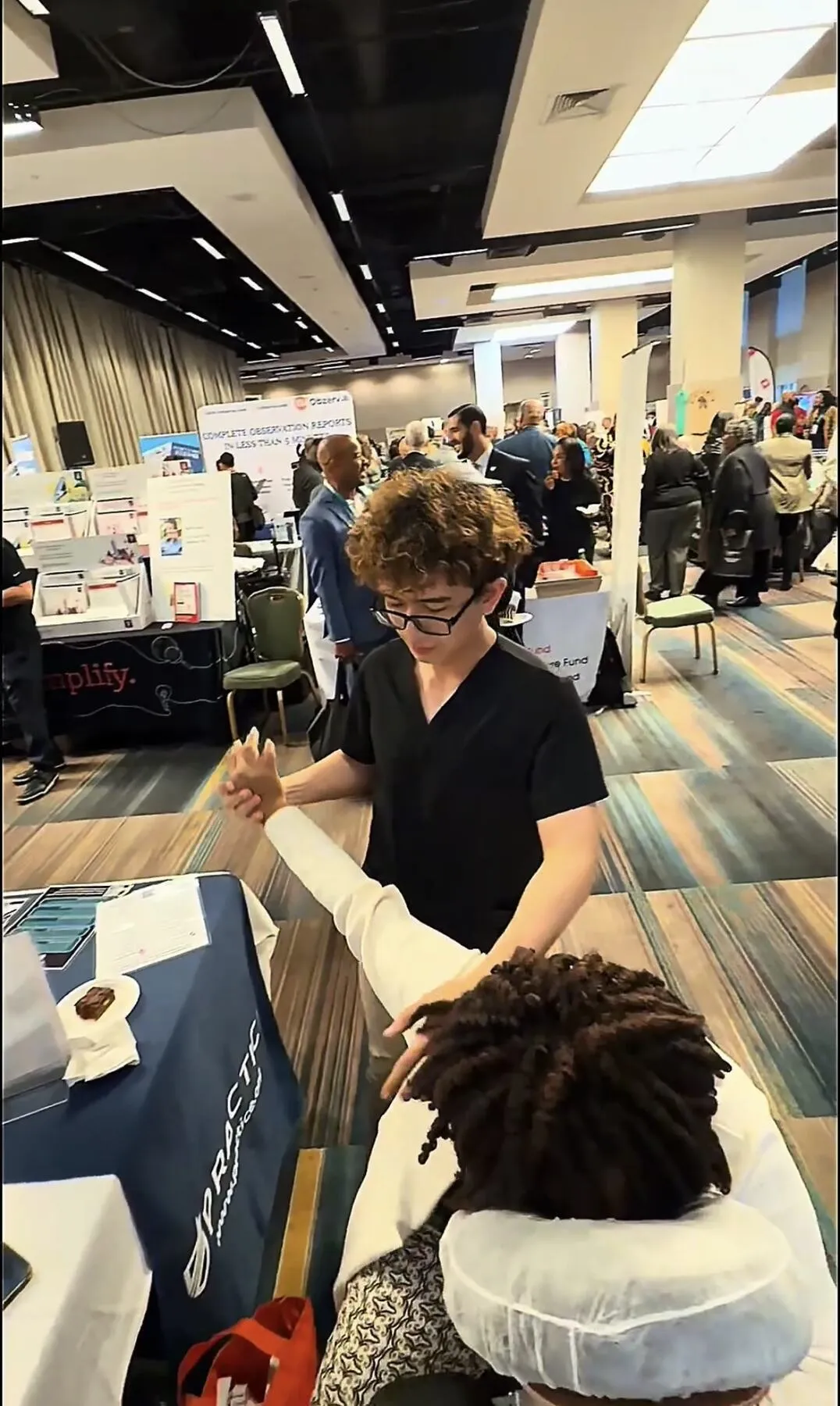 Knead NYC therapist providing hand massage at a busy New York City trade show