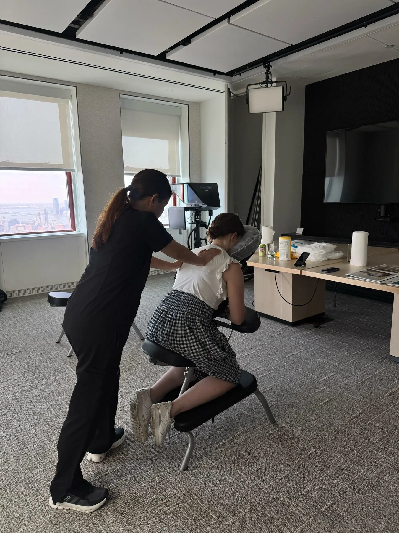 Therapist providing chair massage in a partitioned corporate wellness space