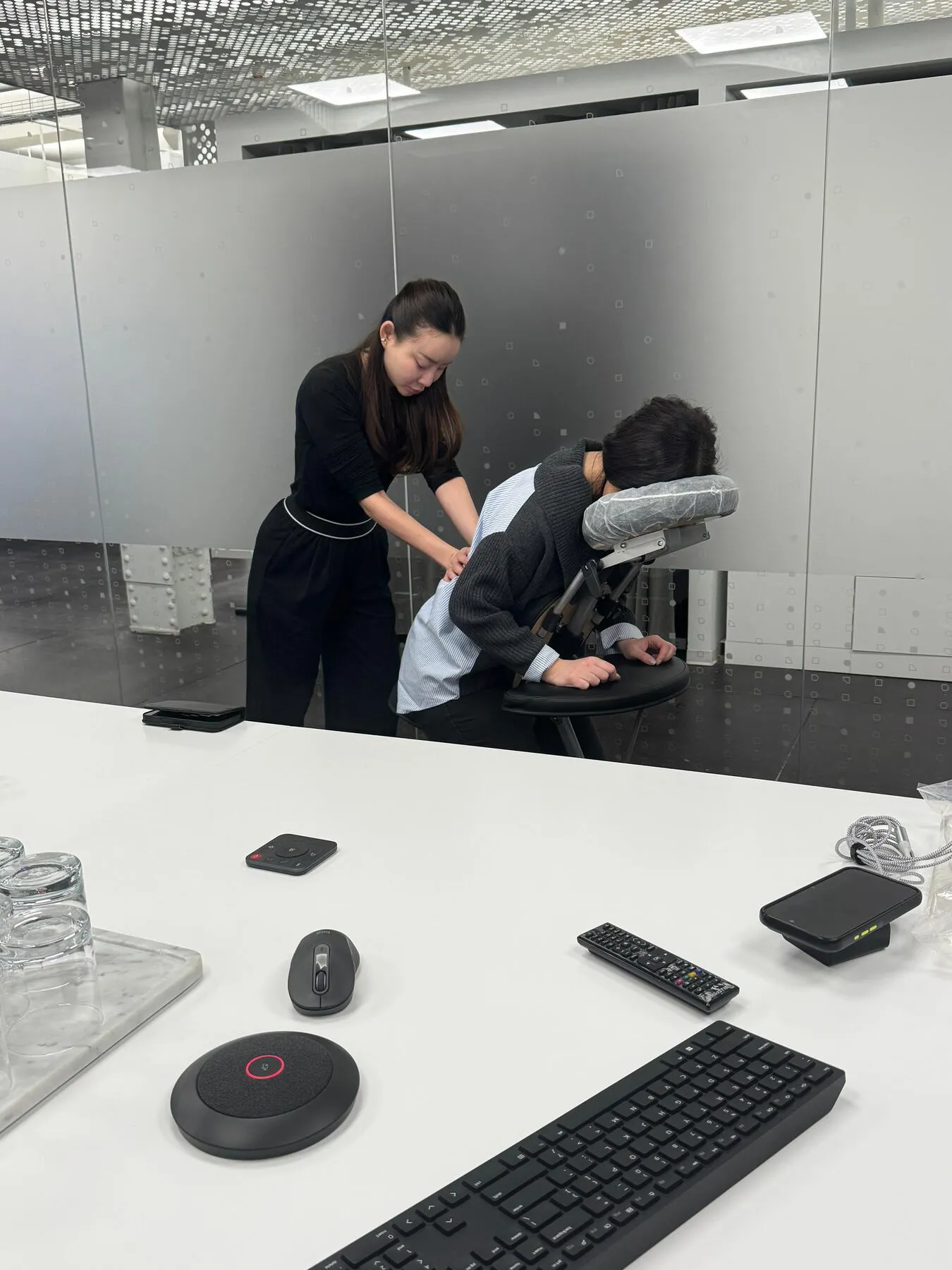 Knead NYC therapist providing chair massage in a modern office conference space
