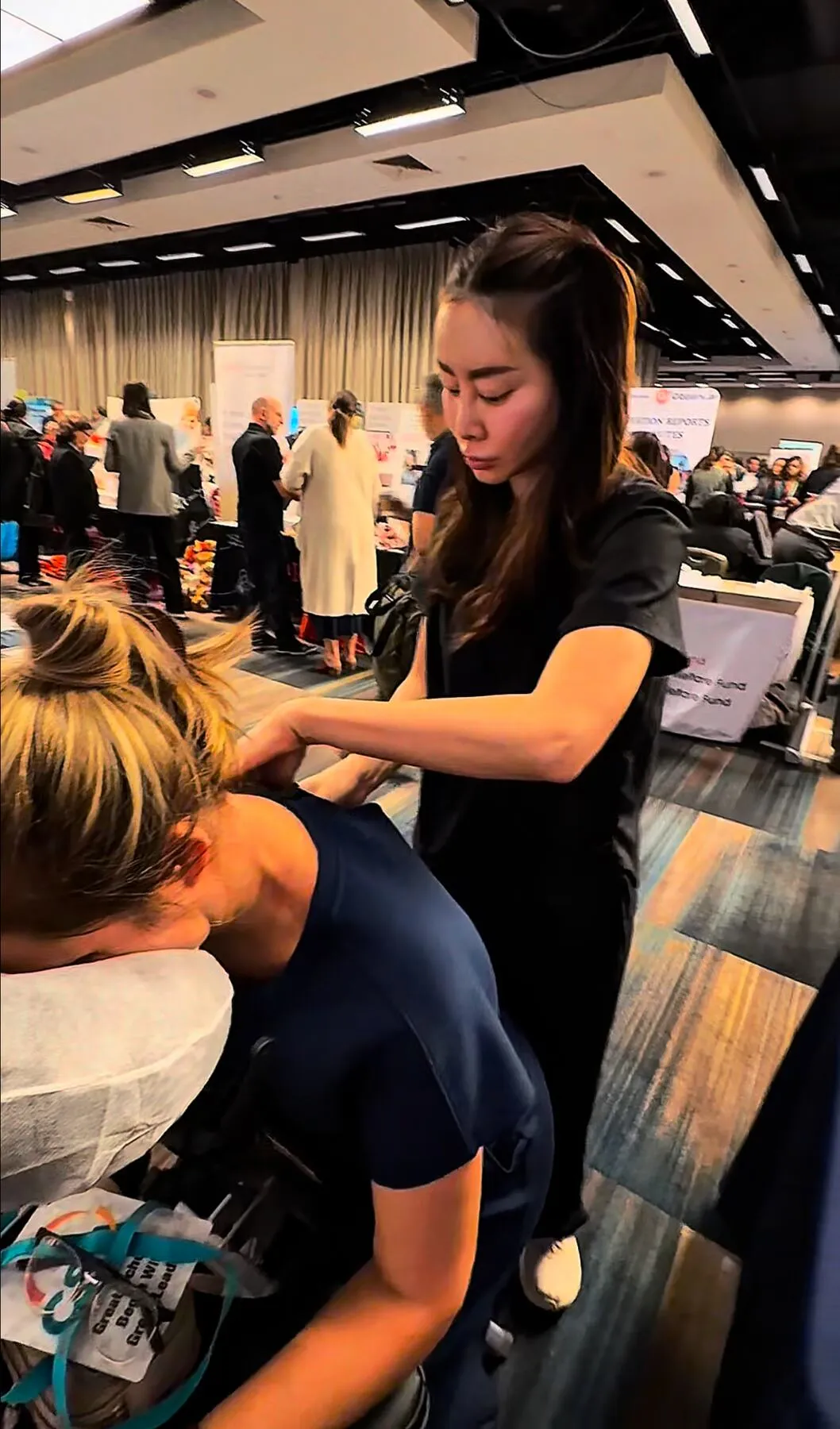 Therapist providing hand and forearm massage at a New York City trade show booth